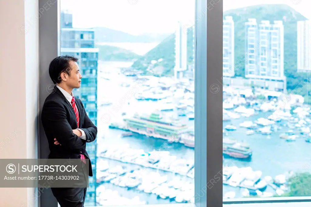 Businessman looking out of window at view of harbour