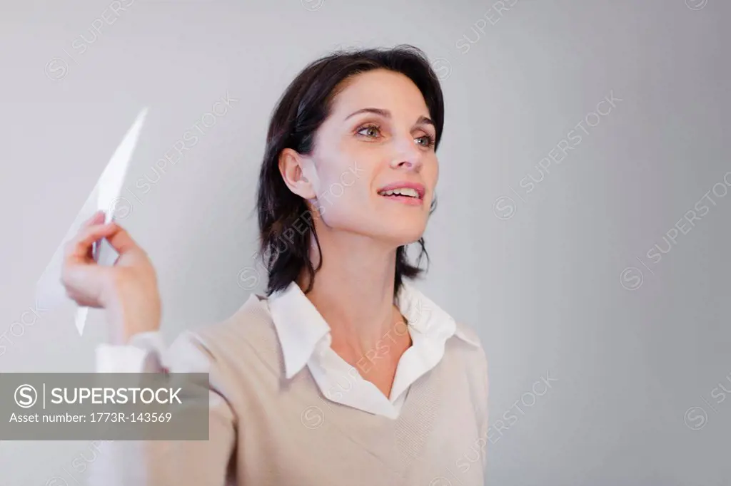 Businesswoman throwing paper airplane