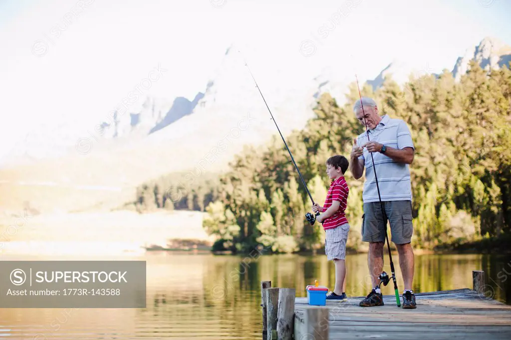 Boy fishing with grandfather in lake