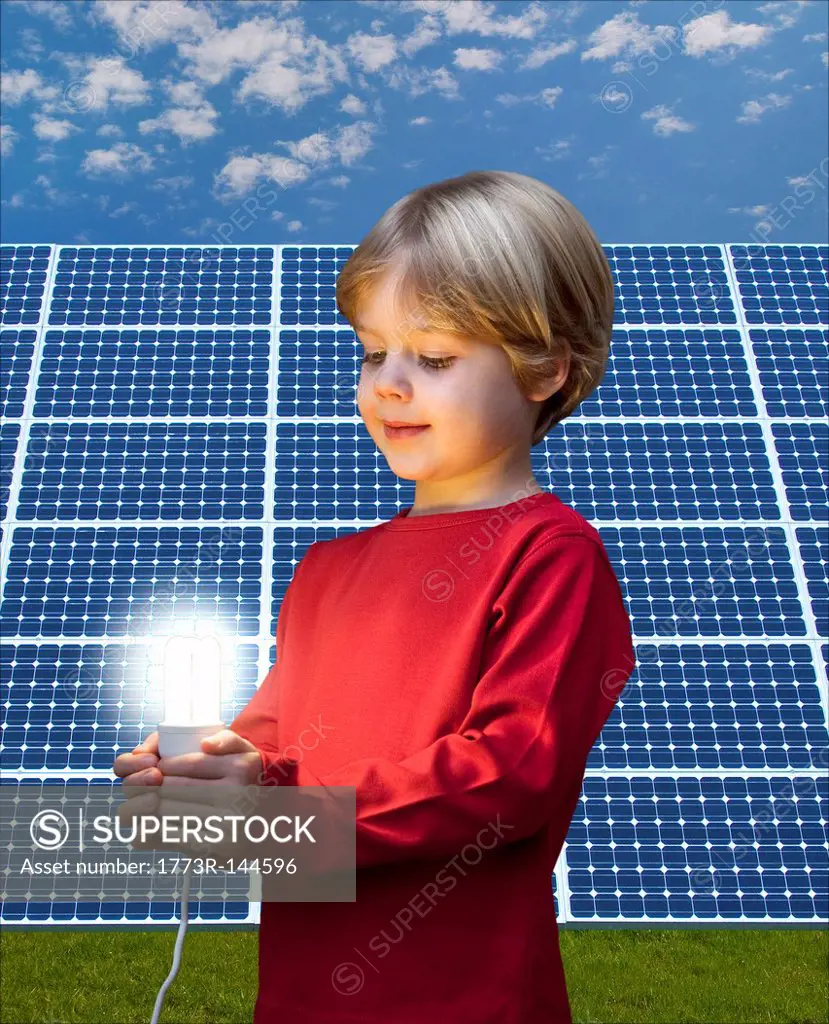 Boy with light bulb by solar panel