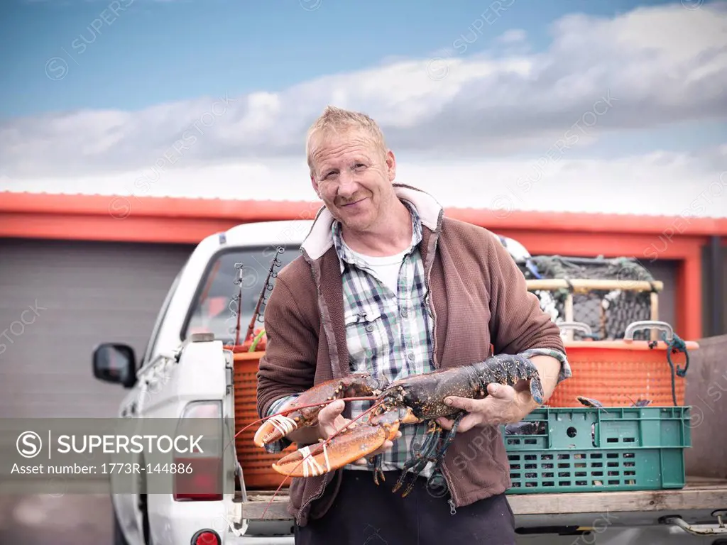 Fisherman holding lobster by truck