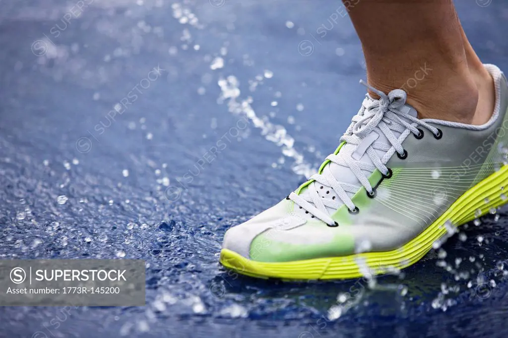 Running shoe splashing water on track