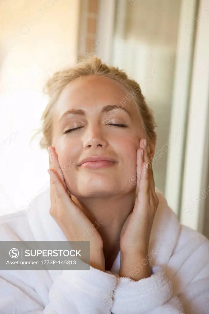 Woman rubbing moisturizer on face