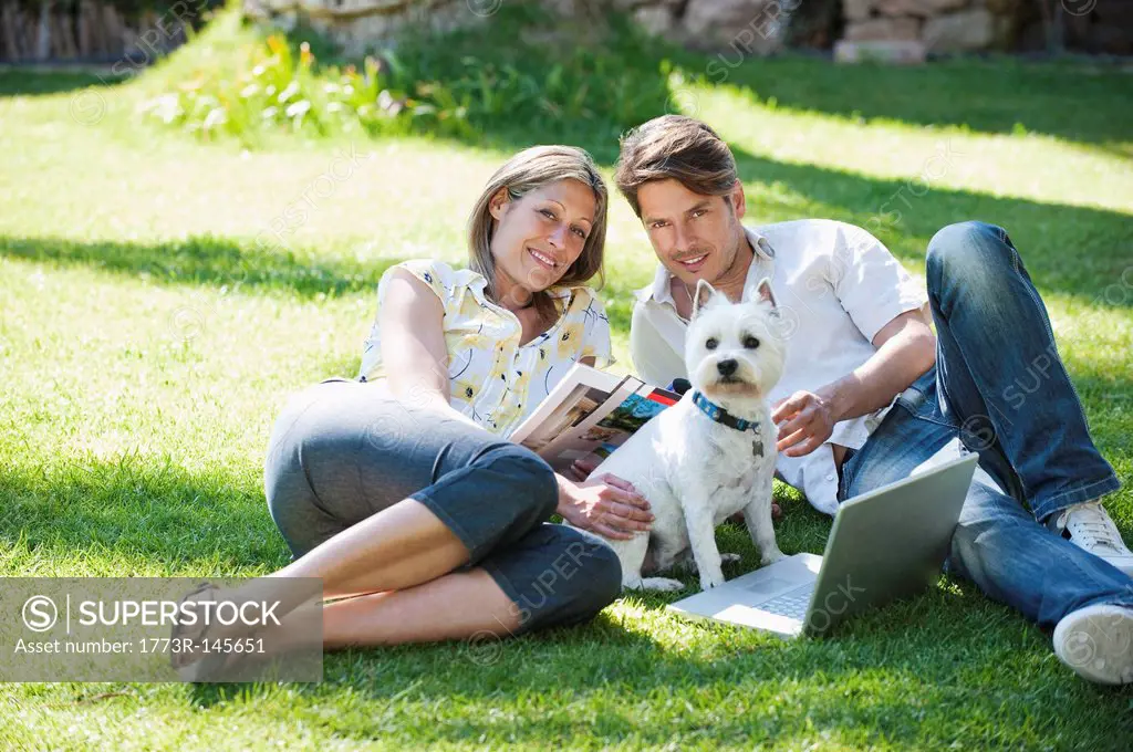 Couple relaxing with dog in grass