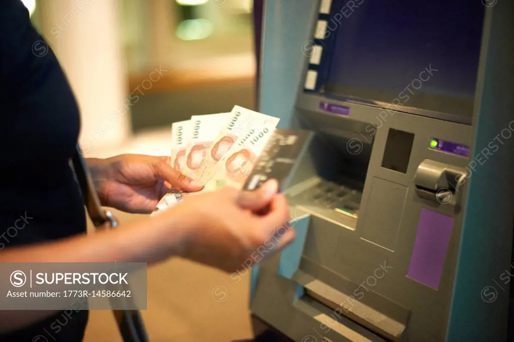 Cropped view of woman withdrawing money from cash machine