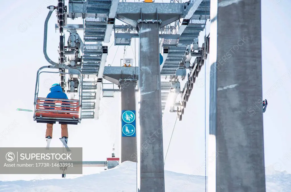 Skier on ski lift, rear view