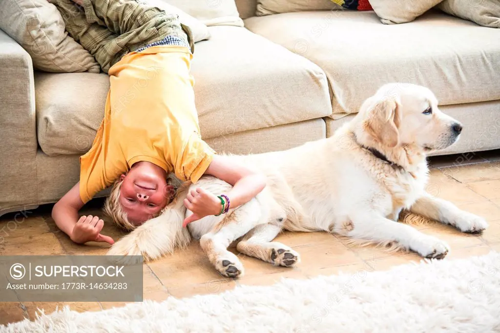 Boy lying upside down on sofa with dog