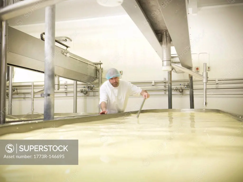 Worker mixing cheese in factory