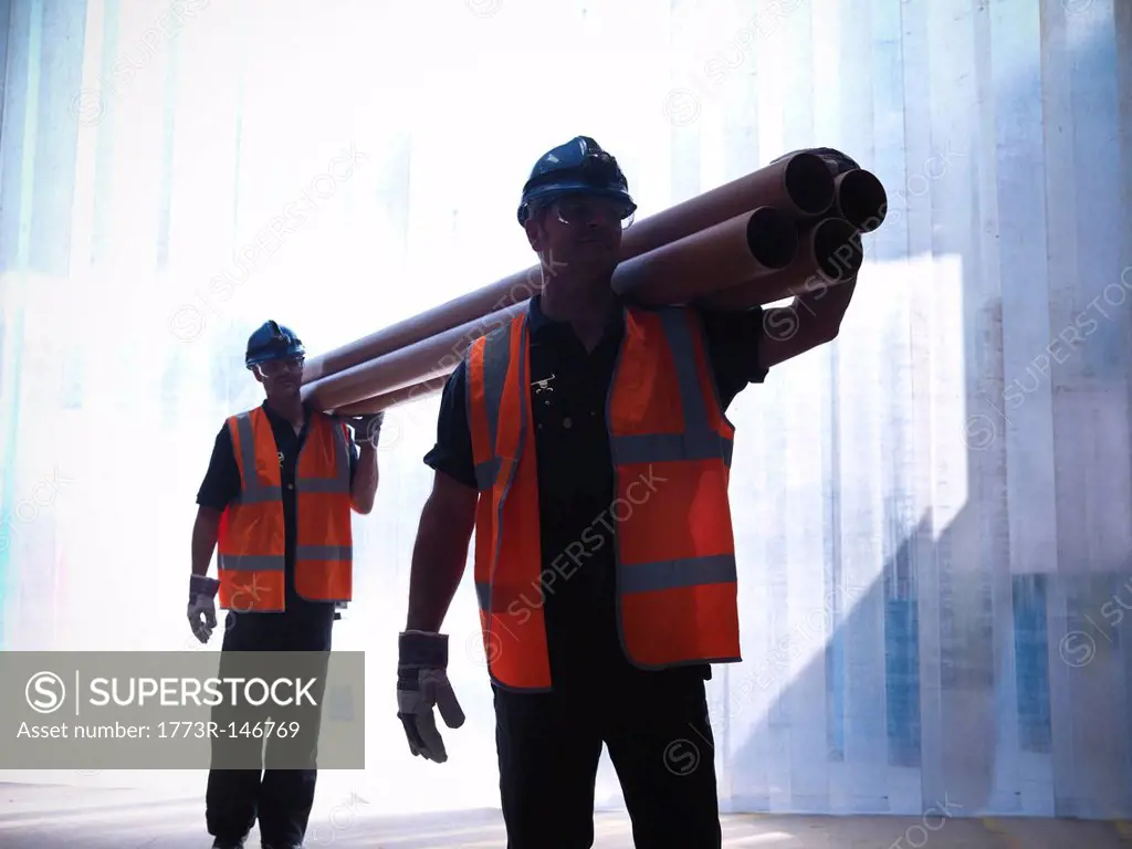 Workers carrying pipes together