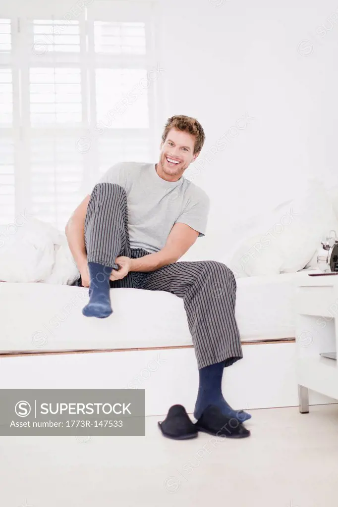 Man putting socks on in bed