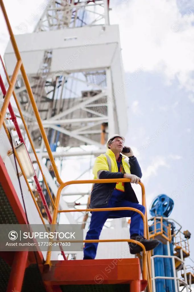 Worker talking on cell phone on oil rig