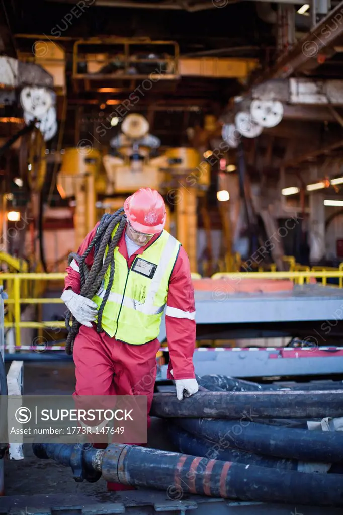 Worker carrying rope on oil rig
