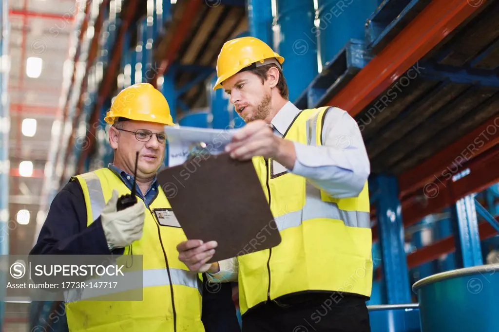 Workers reading clipboard in warehouse