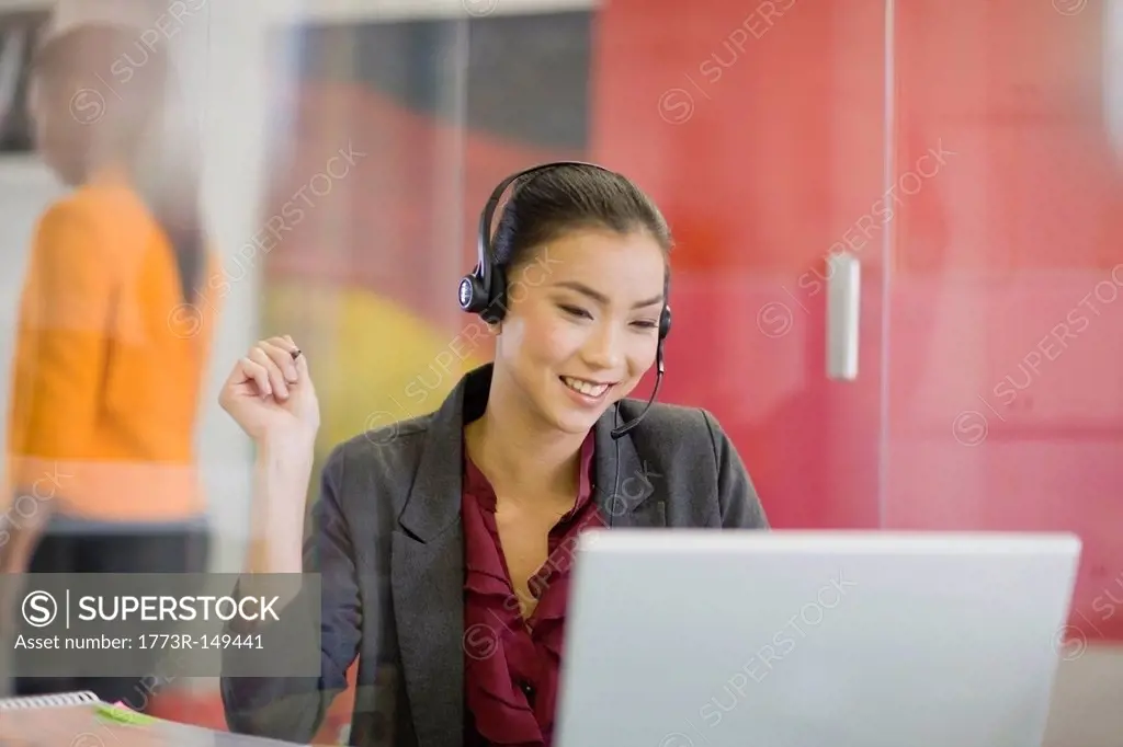 Businesswoman on headset using laptop