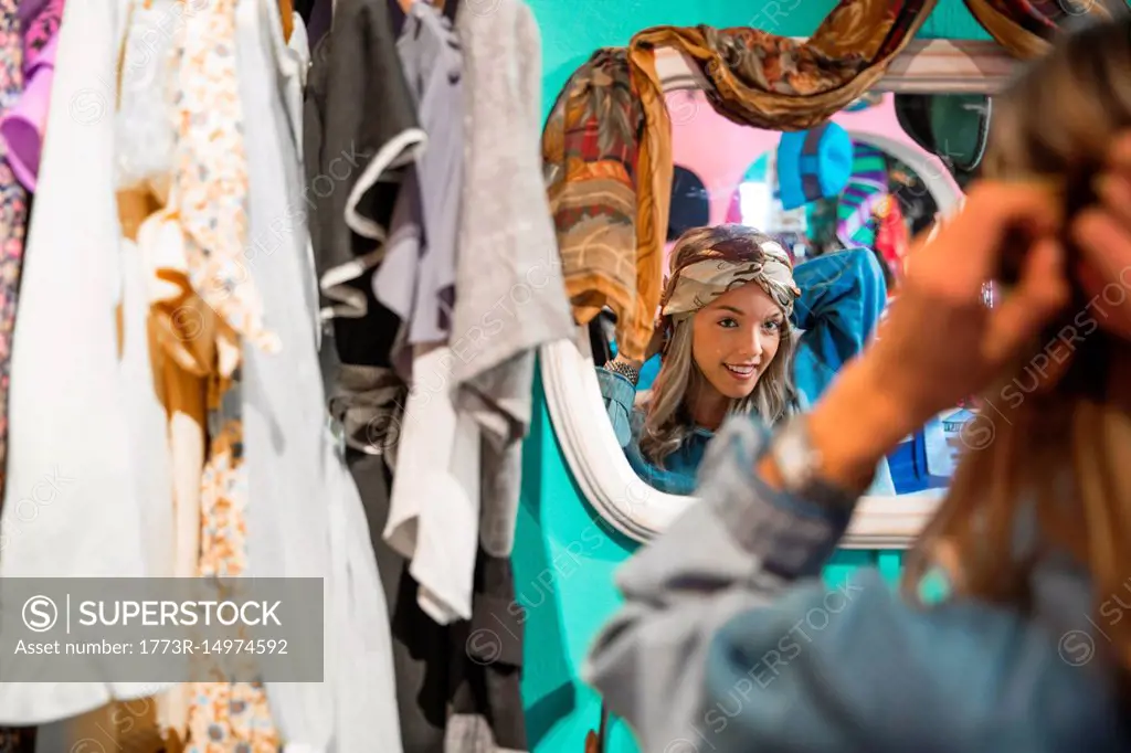 Mirror image of young woman trying on vintage clothes in thrift store