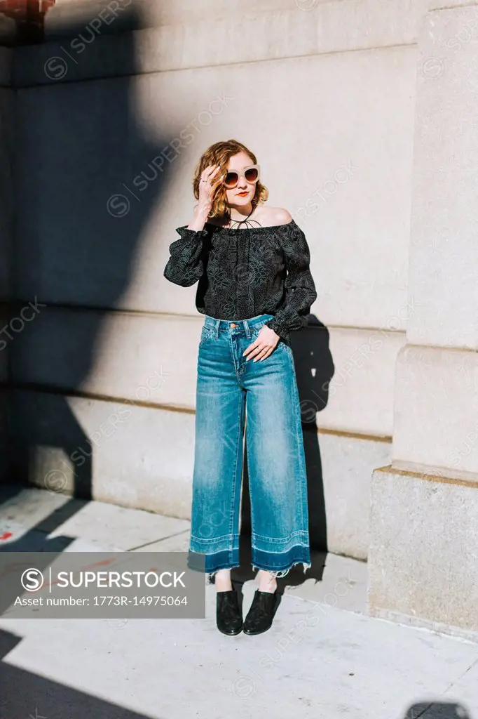Portrait of woman wearing flared jeans looking away, full length