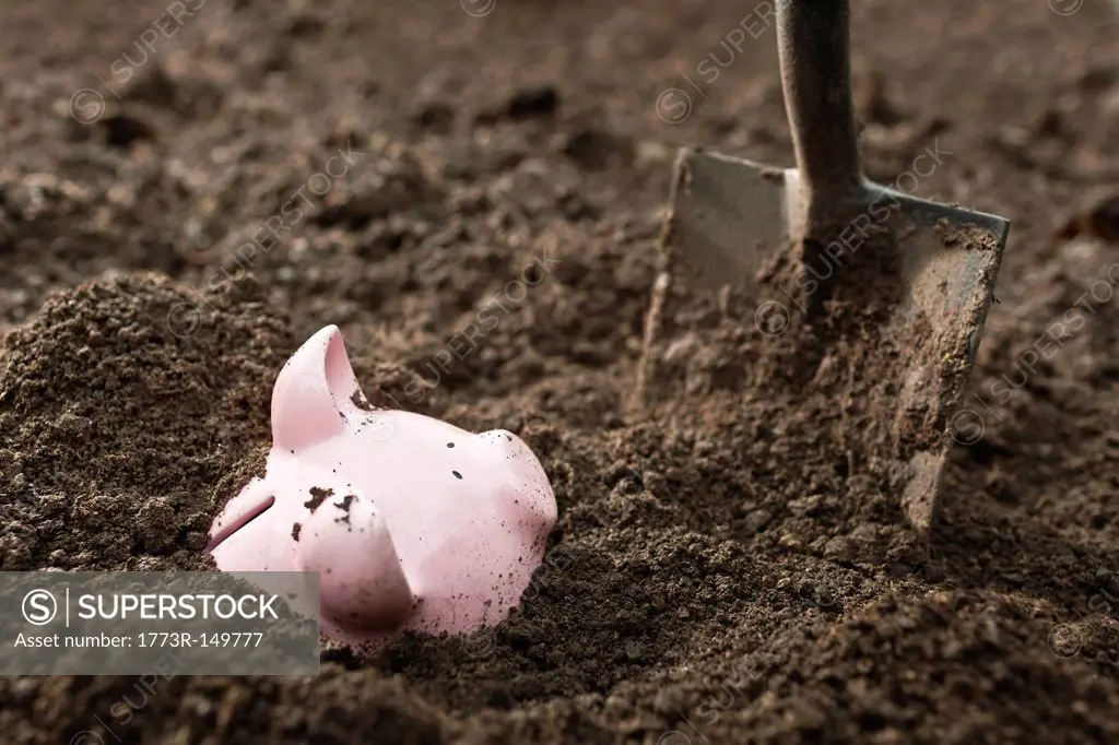 Shovel digging up piggy bank