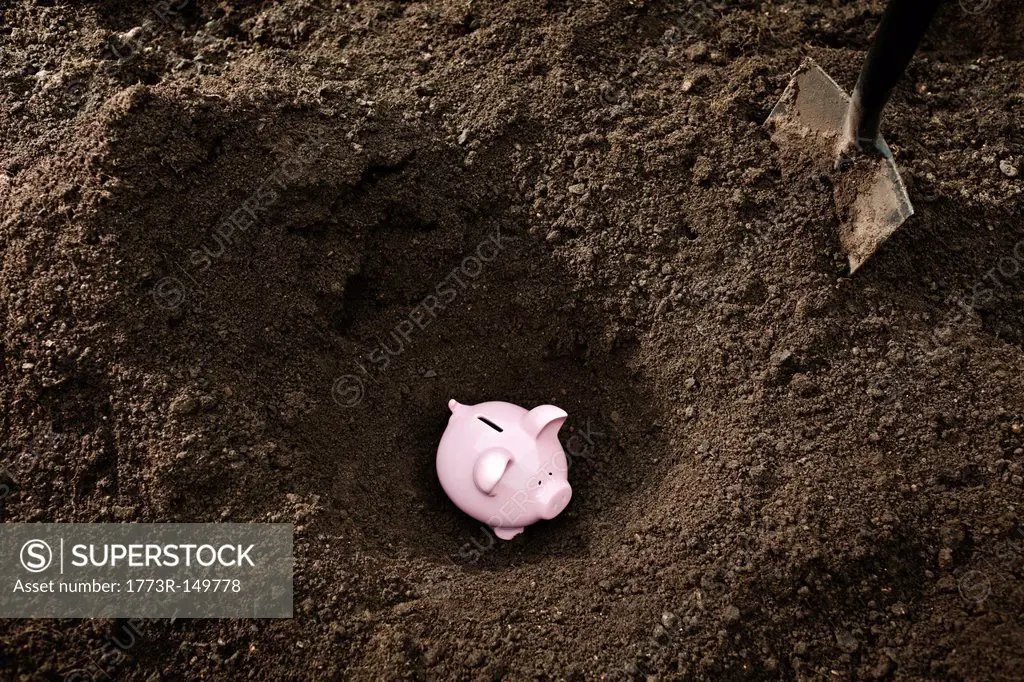 Shovel digging up piggy bank