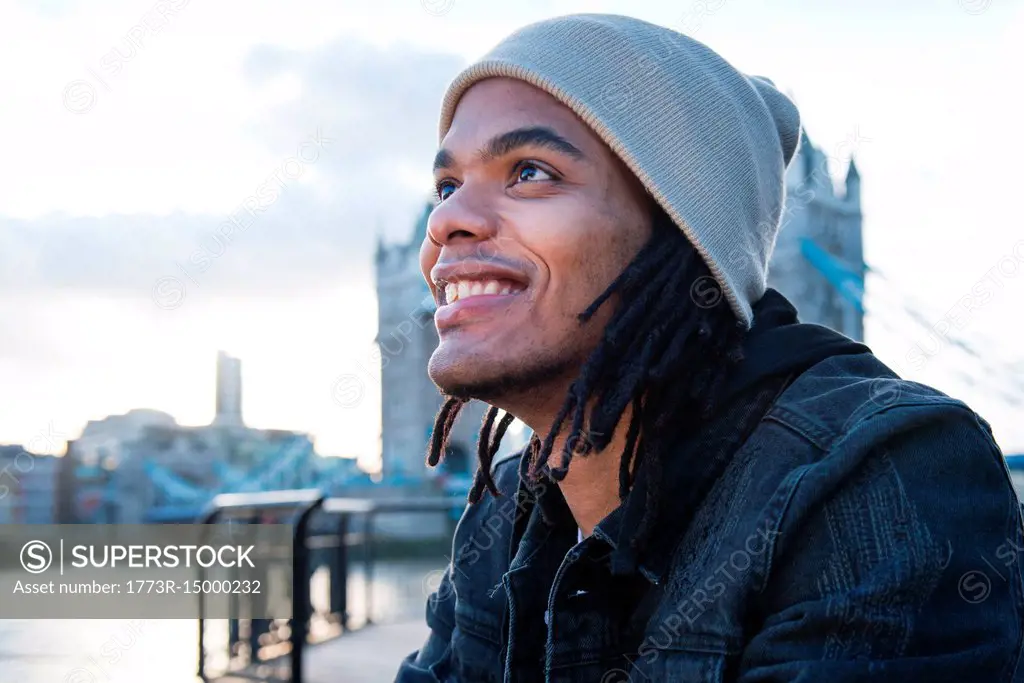 Portrait of young man sitting outdoors, smiling, London, England, UK