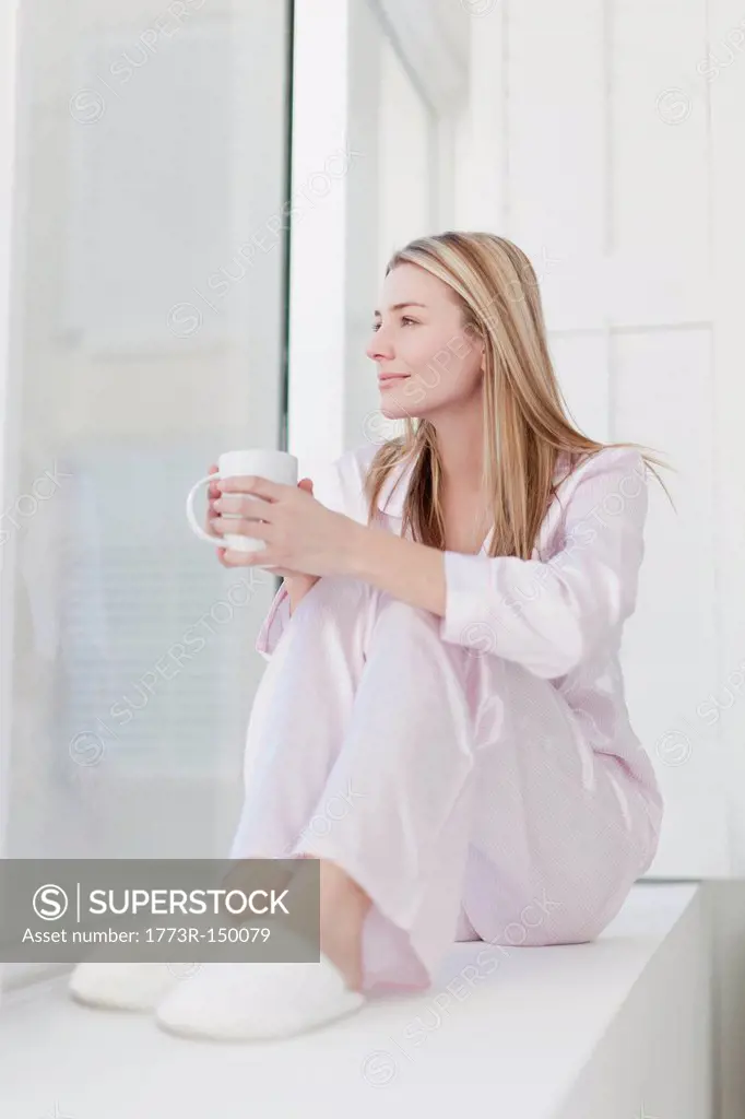 Woman having cup of coffee in pajamas