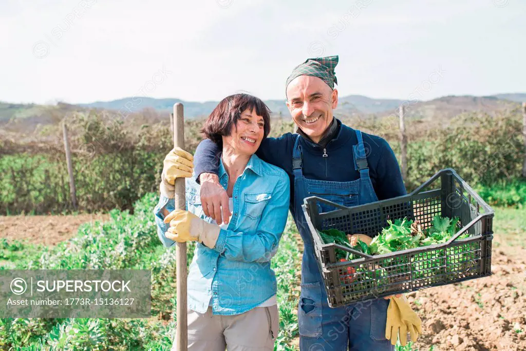 Mature couple with crate of vegetables in garden