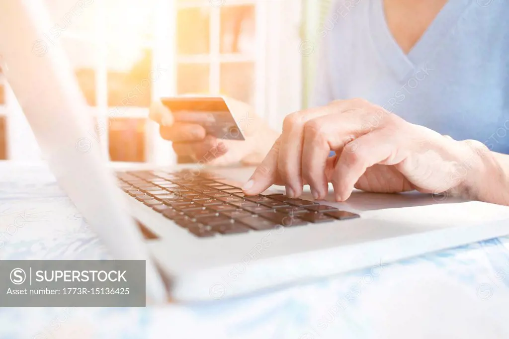 Cropped view of woman holding credit card using laptop