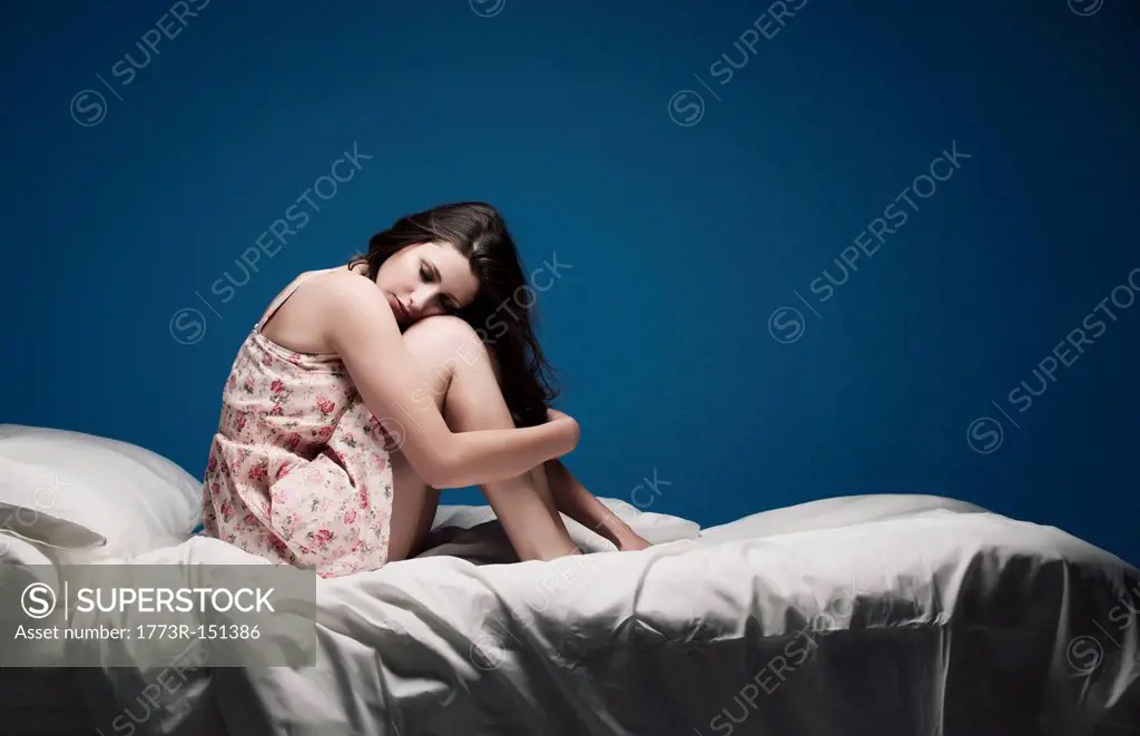 Teenage girl crouching on bed
