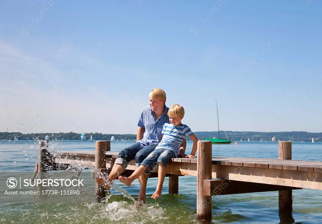 Father and son dangling feet in lake