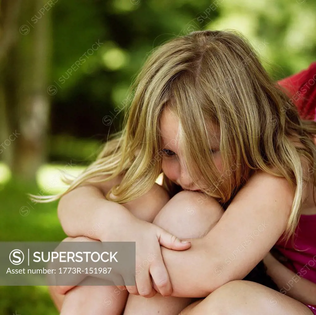 Girl hugging her knees outdoors
