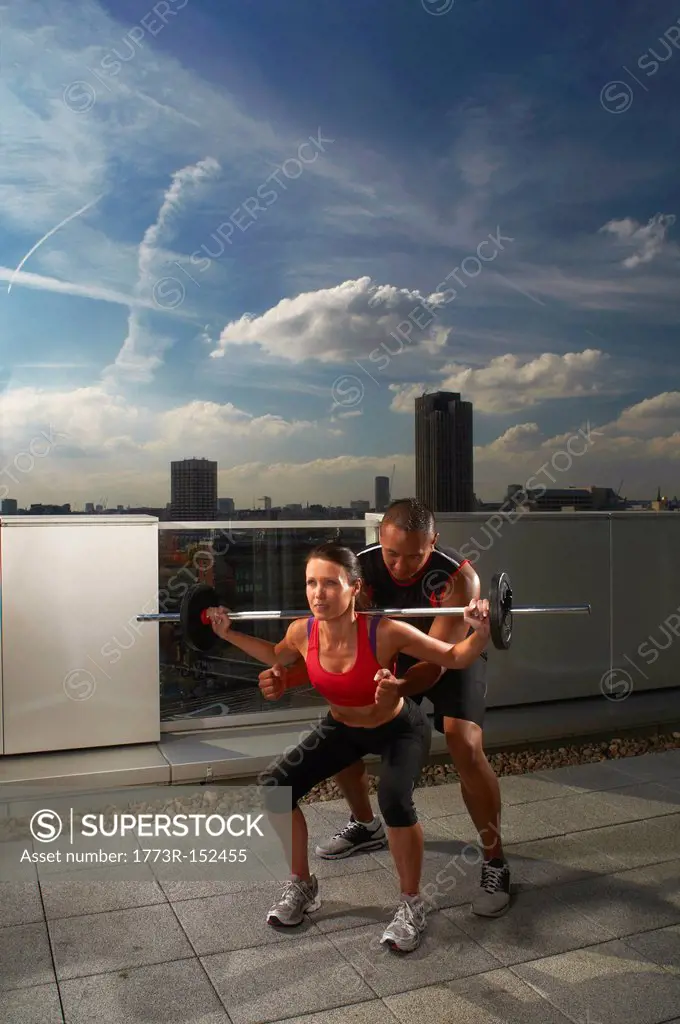 Woman exercising with trainer on rooftop