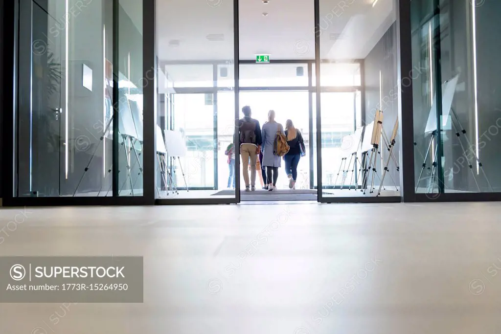 Students leaving college building by glass doors