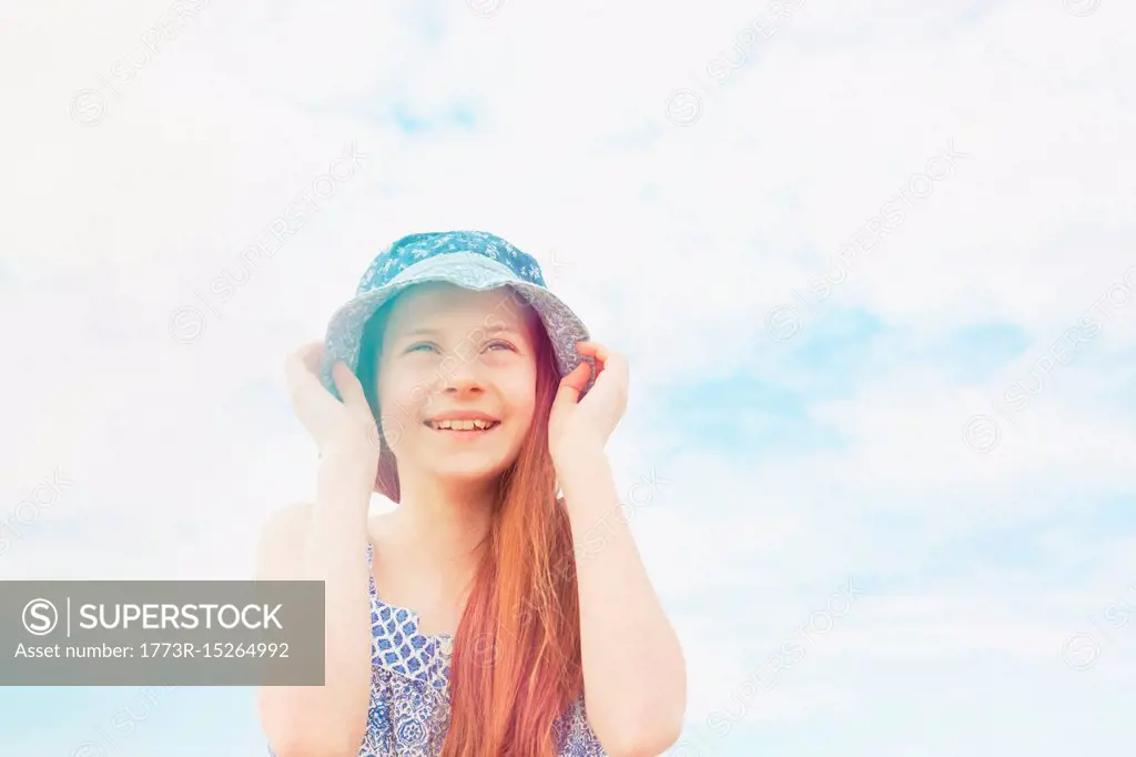 Girl holding down her sun hat
