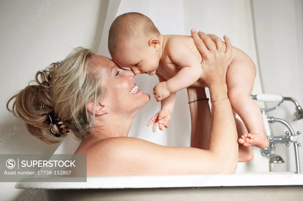 Smiling mother bathing with baby