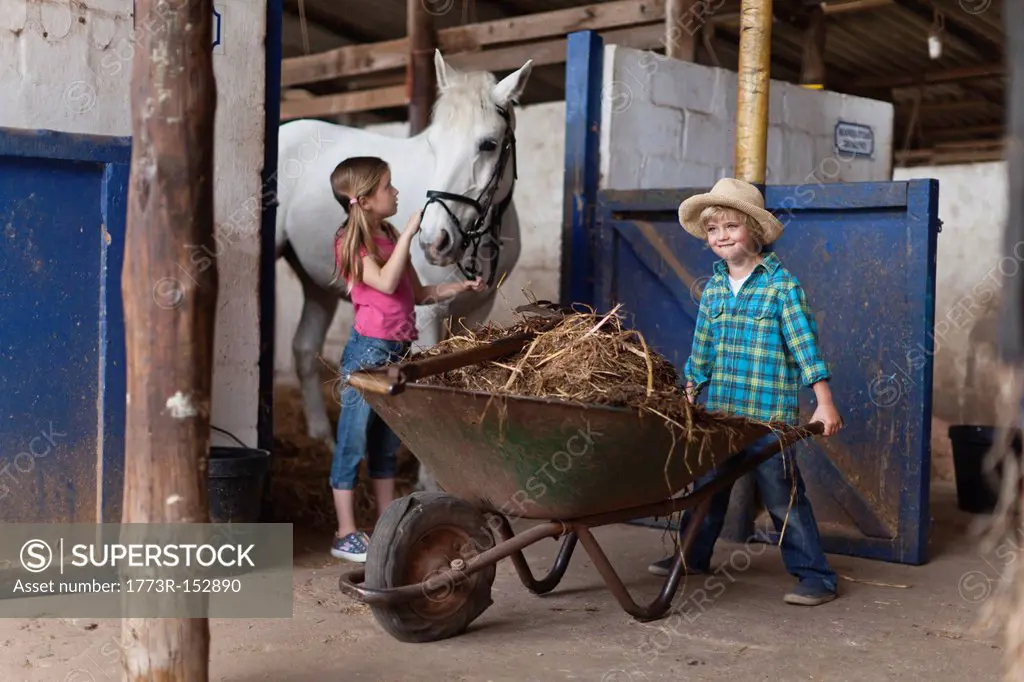 Boy pushing wheelbarrow in stable