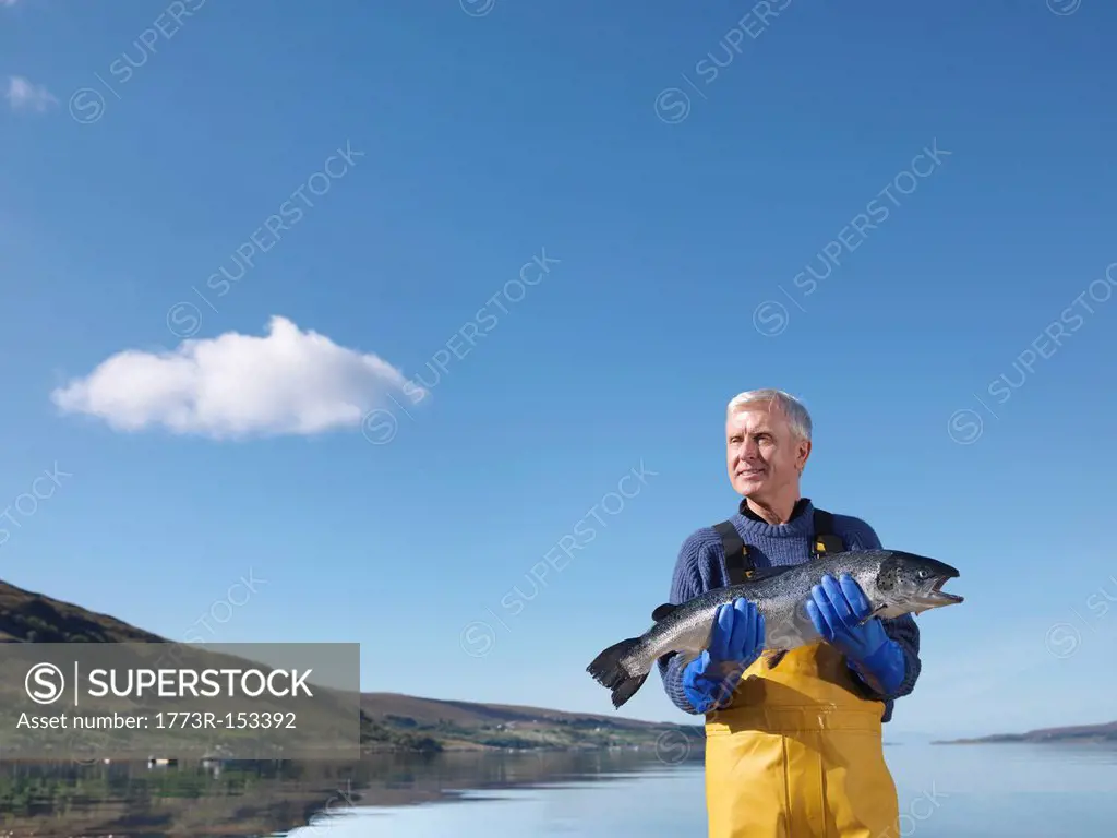 Fisherman holding salmon by lake