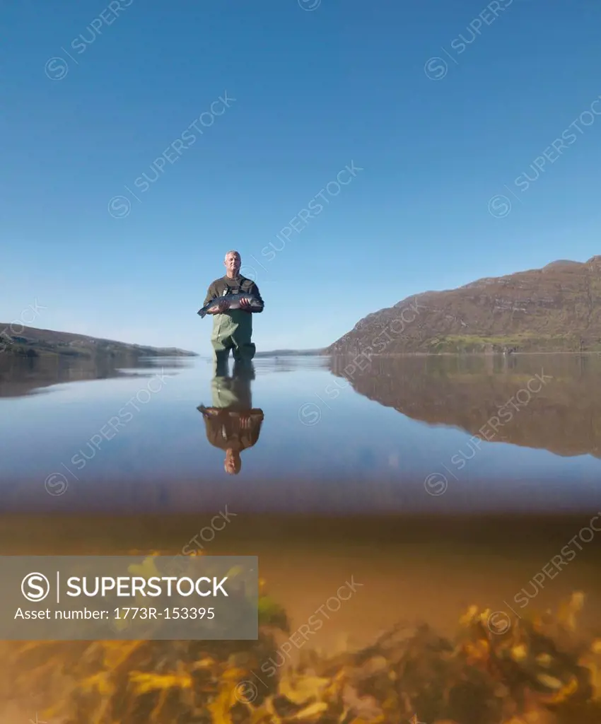 Fisherman with salmon in still lake