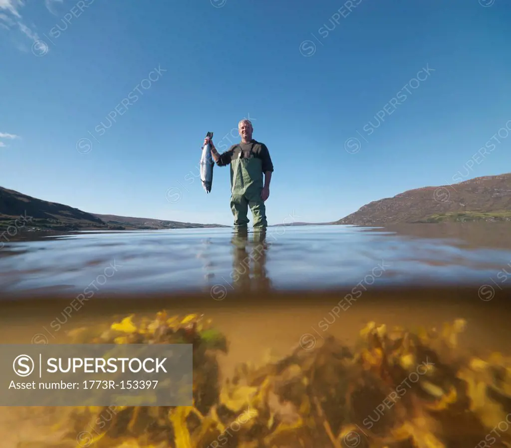 Fisherman with salmon in still lake