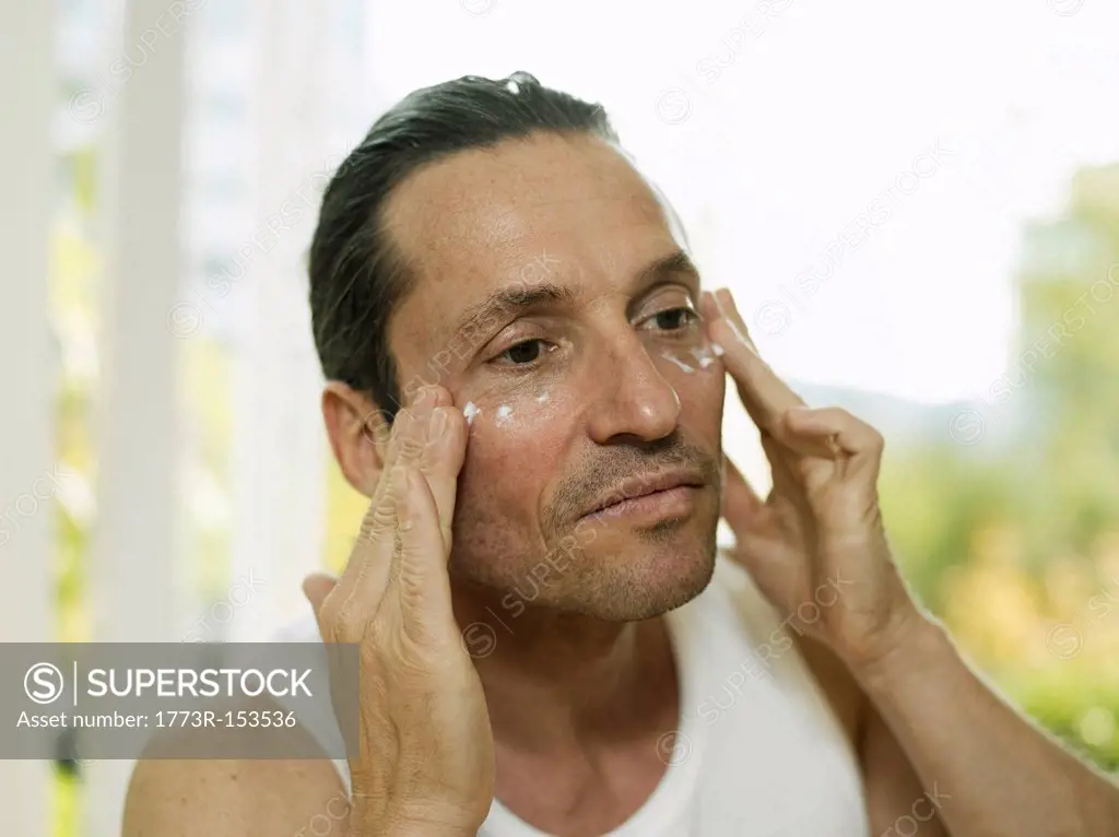 Man applying moisturizer to face