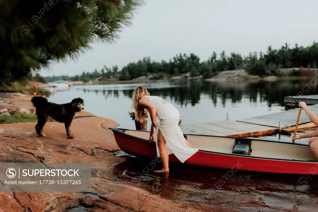 Couple and pet dog getting off boat, Algonquin Park, Canada