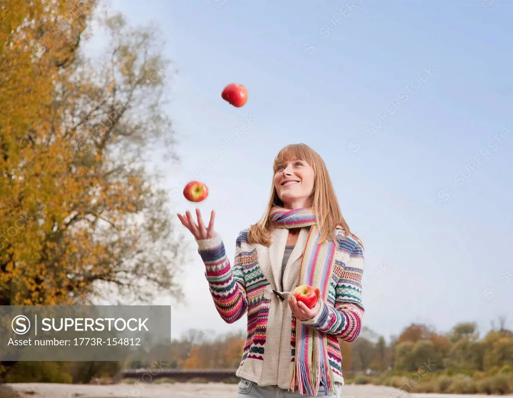 Woman juggling apples outdoors