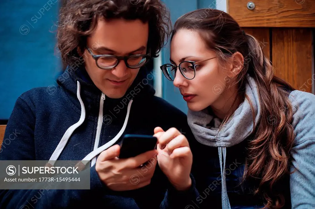 Mid adult man and girlfriend looking at smartphone