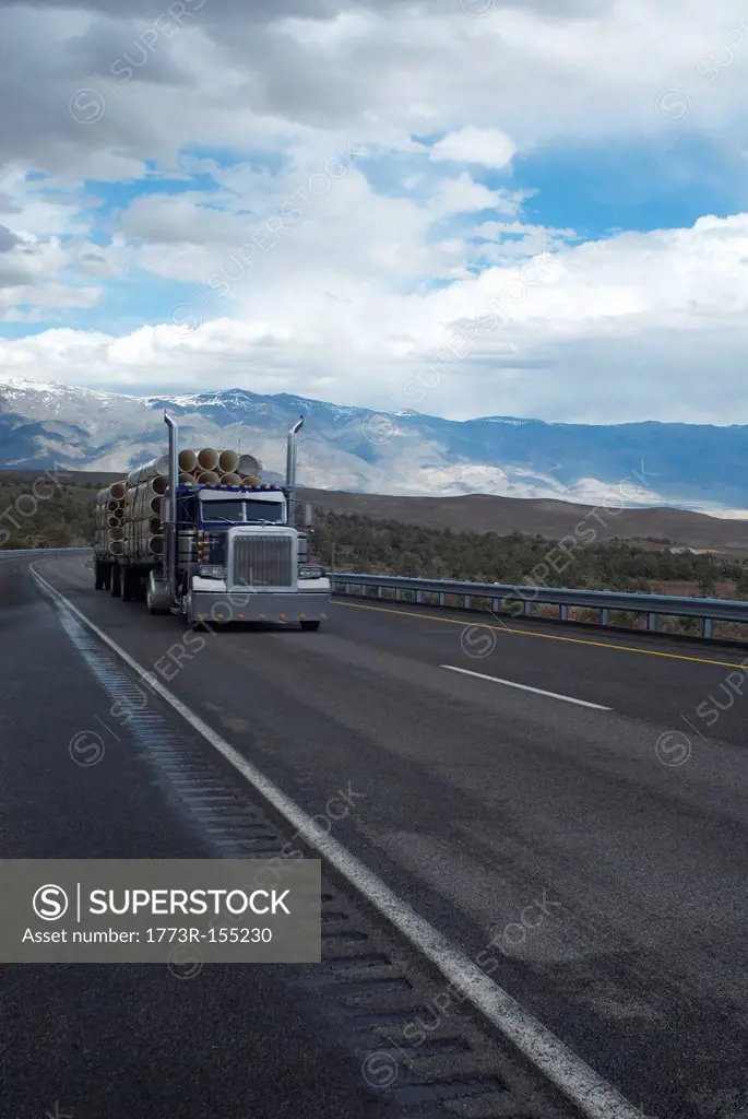 Truck carrying logs in rural landscape