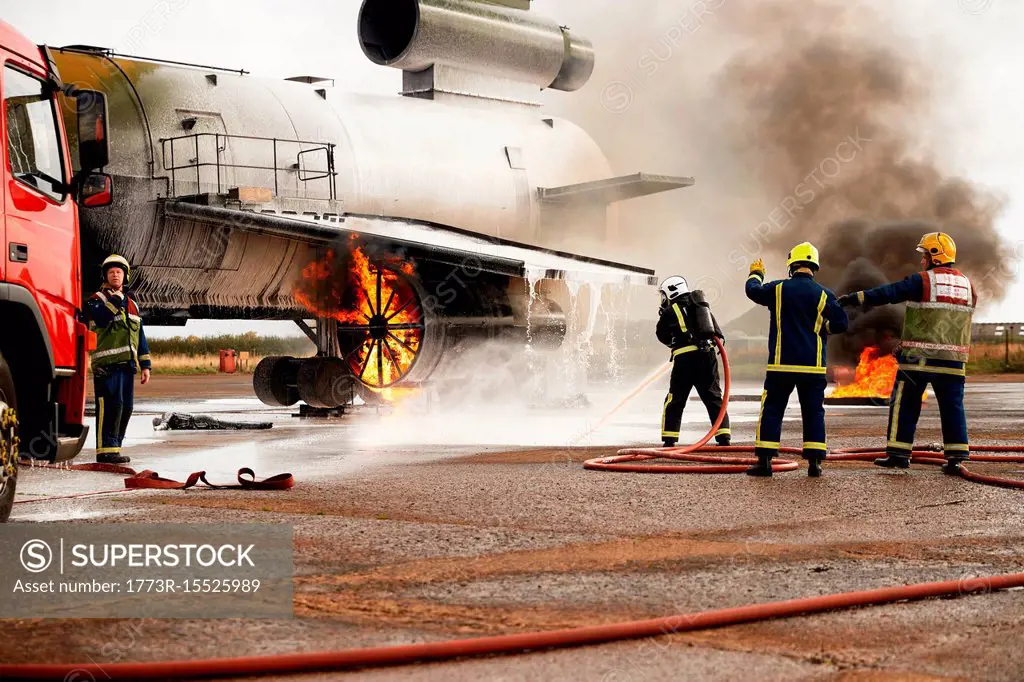 Firemen training, spraying water at mock airplane engine
