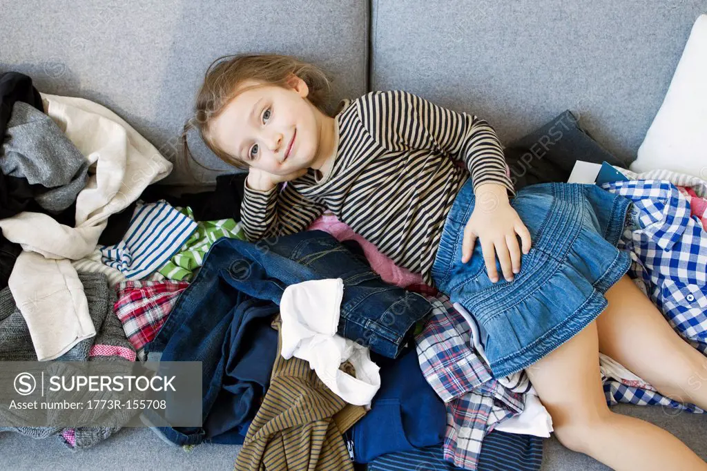 Smiling girl laying on pile of laundry