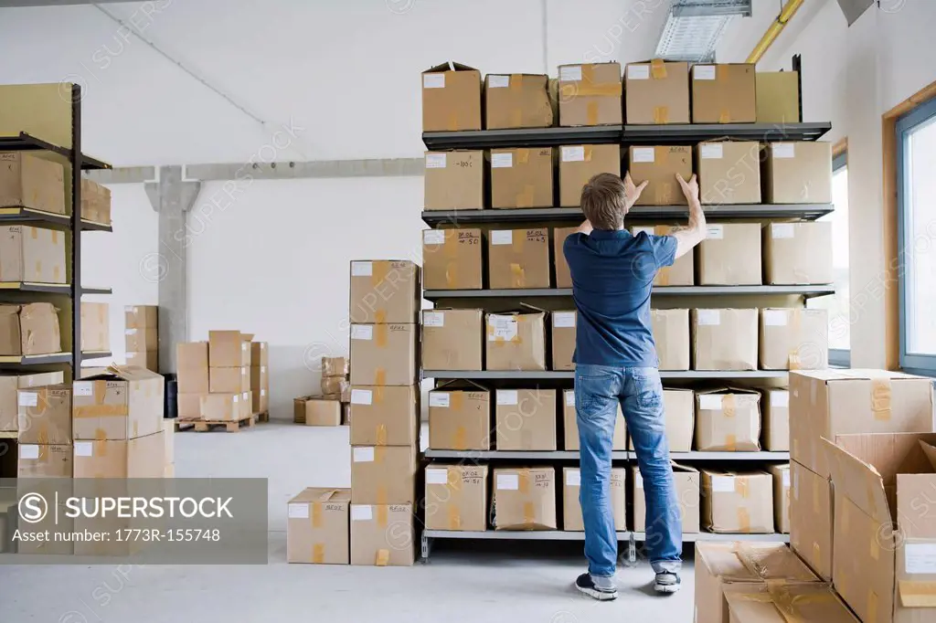 Man filing cardboard boxes in storage