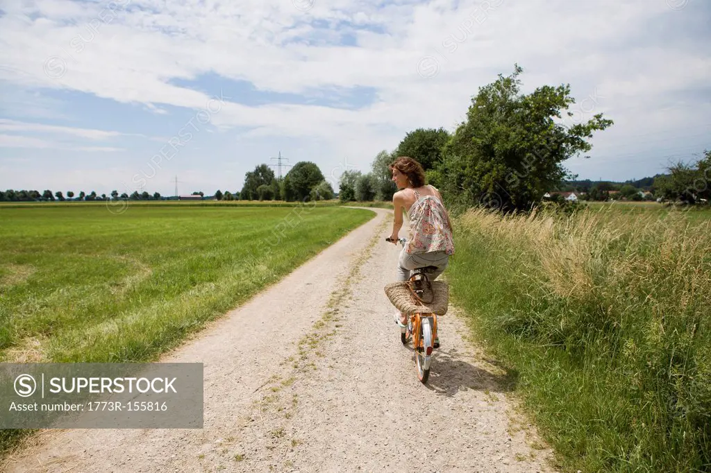 Woman riding bicycle on rural road