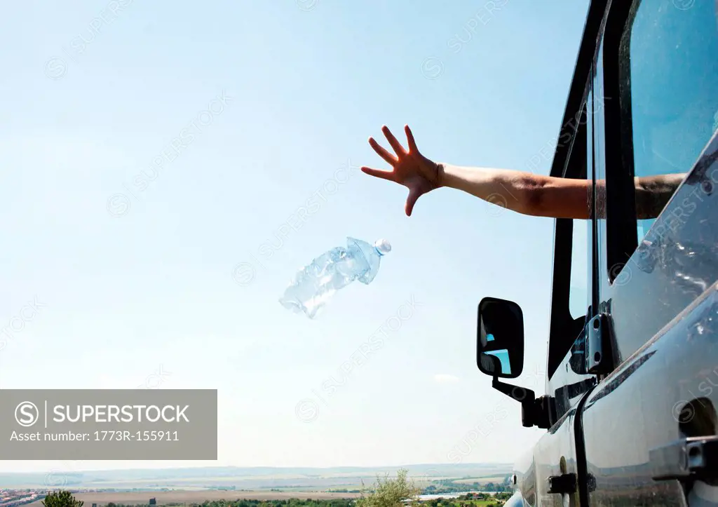 Woman throwing bottle out car window