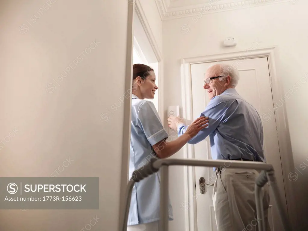 Nurse talking to older man in house