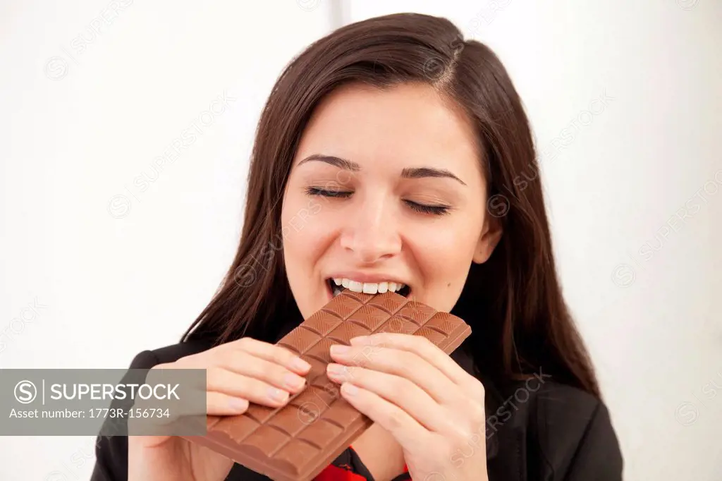Businesswoman eating bar of chocolate