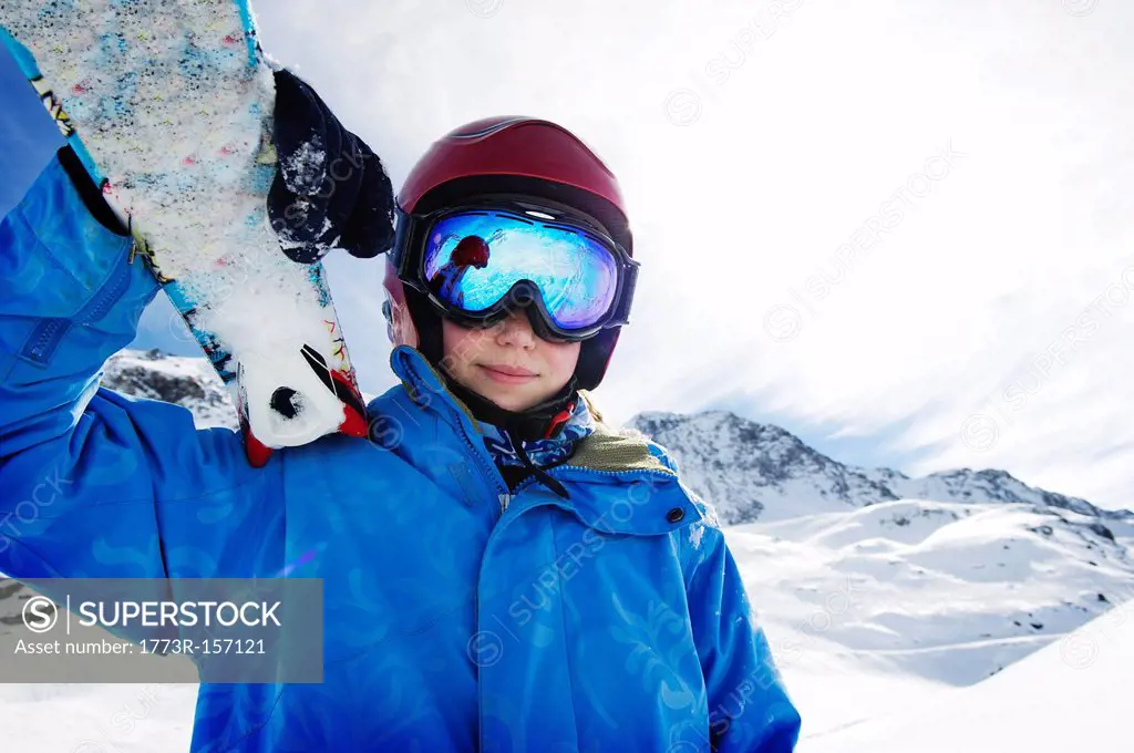 Boy holding skis on snowy mountain